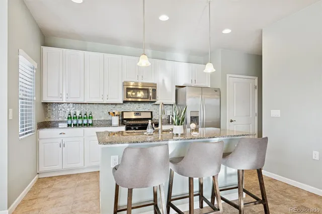 a kitchen with a sink dishwasher a dining table and chairs with wooden floor