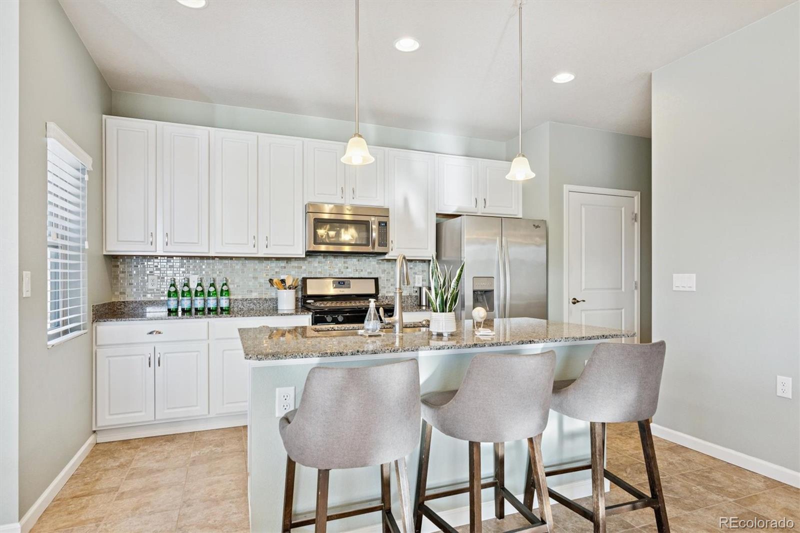 2028 South Flanders Way, Unit A Aurora, CO 80013 - Photo 4 of 30 a kitchen with kitchen island white cabinets and stainless steel appliances