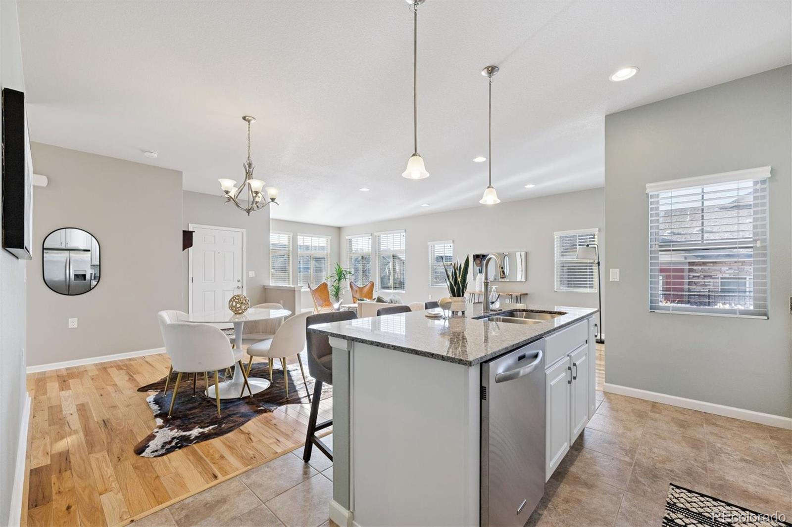 2028 South Flanders Way, Unit A Aurora, CO 80013 - Photo 5 of 30 a kitchen with a sink dishwasher a dining table and chairs with wooden floor