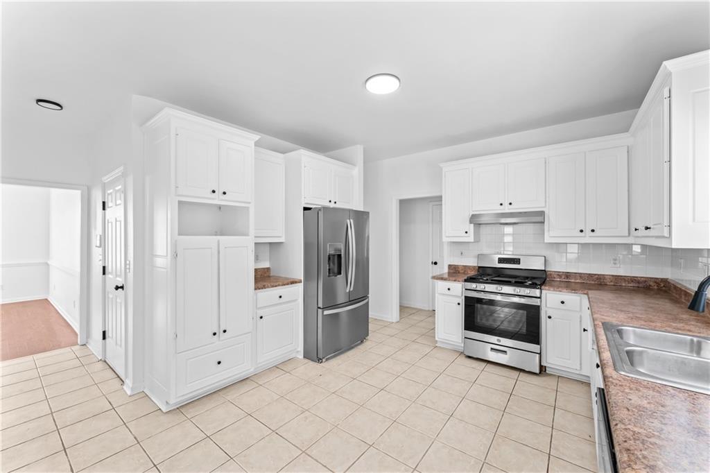 4267 Azalea Walk Ellenwood, GA 30294 - Photo 7 of 24 a kitchen with white cabinets and stainless steel appliances