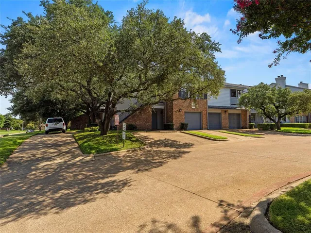 a front view of a house with a yard and a large tree