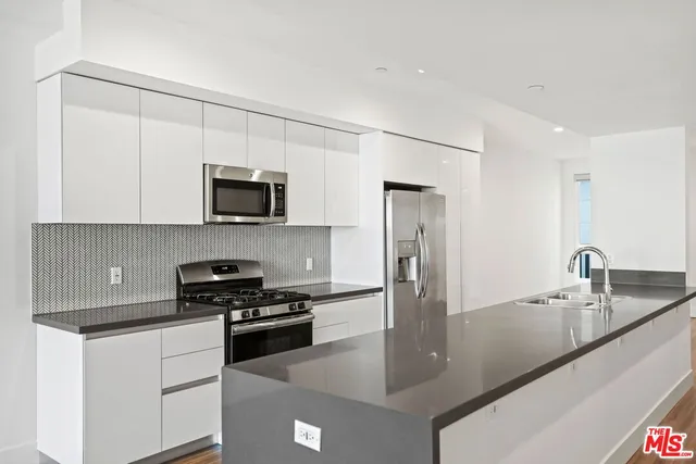 a kitchen with stainless steel appliances granite countertop a sink a stove and a refrigerator