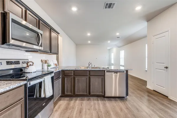a kitchen with stainless steel appliances granite countertop a stove a sink and a microwave