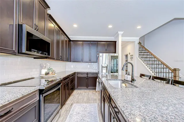 a kitchen with stainless steel appliances granite countertop a sink a stove top oven and refrigerator