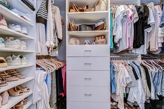 a view of walk in closet with clothes and shoes