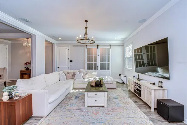 a living room with furniture a flat screen tv and a chandelier