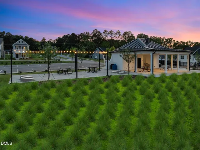 a view of a white house with a big yard and potted plants