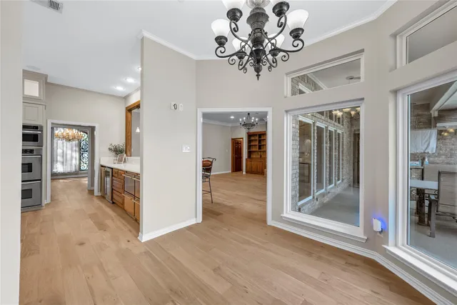 a view of a hallway with wooden floor and a chandelier