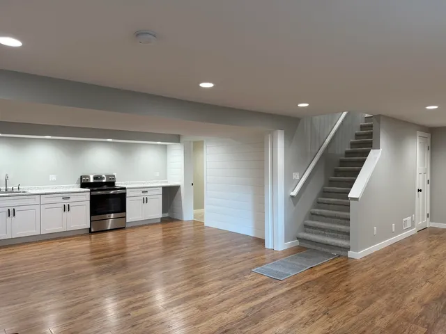 a view of a kitchen with wooden floor electronic appliances and stairs