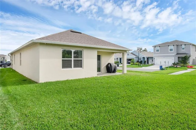 a view of a yard in front of a house with plants and large tree