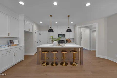 a kitchen with stainless steel appliances granite countertop a sink a stove a refrigerator and white cabinets