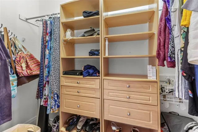 a view of walk in closet with clothes and shoes