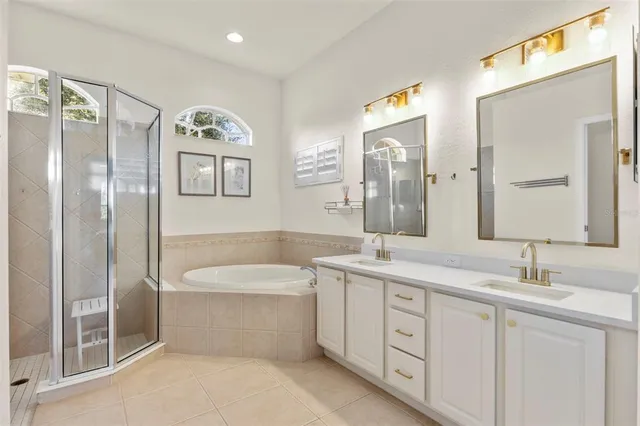 a bathroom with a double vanity sink a large mirror a bathtub and shower