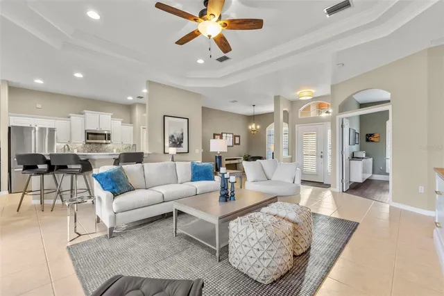 a living room with furniture kitchen view and a chandelier