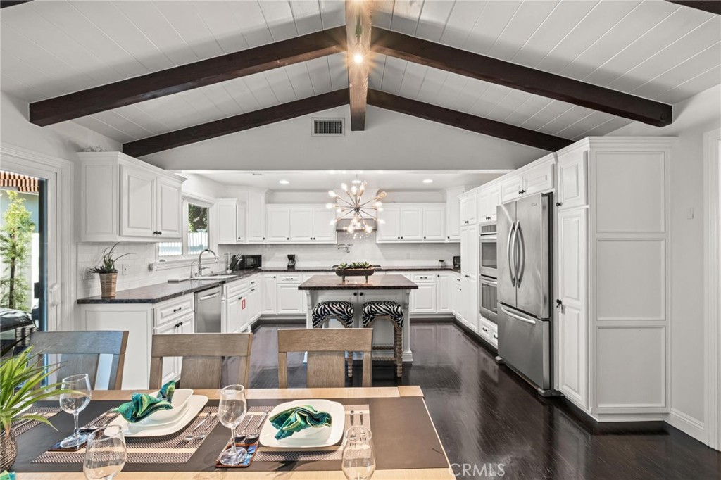 a kitchen with stainless steel appliances granite countertop a refrigerator a stove and white cabinets with wooden floor