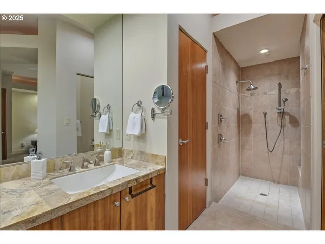 a bathroom with a granite countertop sink a mirror and shower