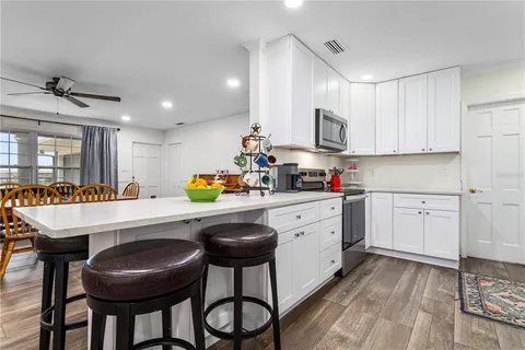 a kitchen with stainless steel appliances kitchen island granite countertop a table chairs sink and cabinets