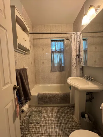 a bathroom with a sink a toilet a window and tub