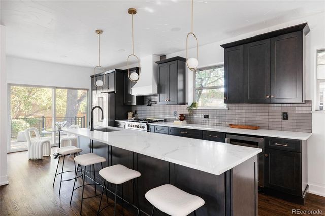 a kitchen with stainless steel appliances granite countertop a sink a stove a table and chairs