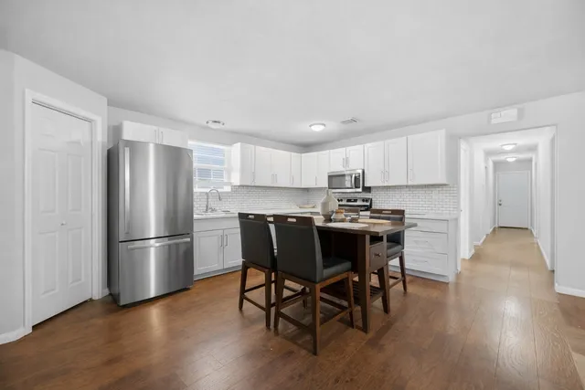 a kitchen with stainless steel appliances granite countertop a table chairs refrigerator sink and cabinets