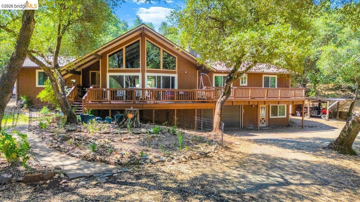 8733 Fraguero Road Sonora, CA 95370 - Photo 4 of 73 Brown-toned exterior residence featuring a prominent A-frame window design, an expansive wooden deck, and a multi-level structure