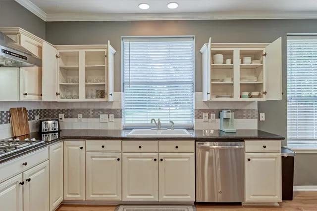 a kitchen with granite countertop a sink window and cabinets