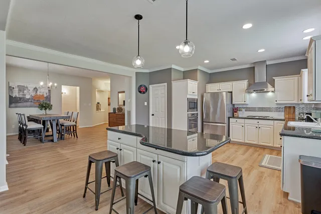 a kitchen with stainless steel appliances kitchen island granite countertop a table chairs and white cabinets
