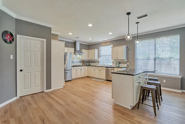 a open kitchen with kitchen island a stove a refrigerator wooden floor and a view of living room