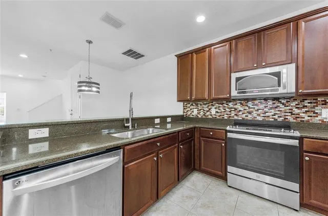a kitchen with stainless steel appliances granite countertop a refrigerator and a sink