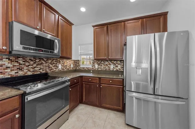 a kitchen with granite countertop a stove a microwave a sink and cabinets