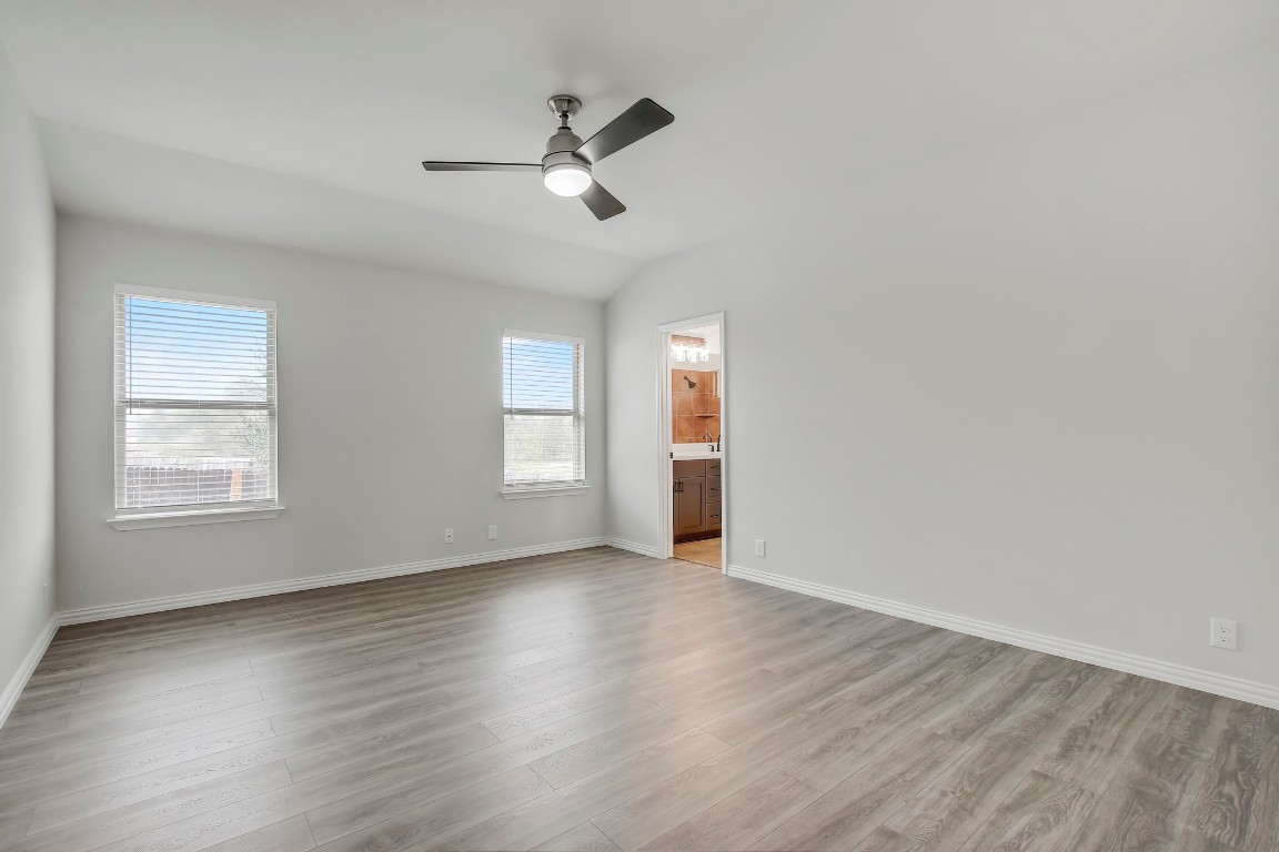 406 Dragon Ridge Road Buda, TX 78610 - Photo 18 of 39 an empty room with wooden floor chandelier fan and windows