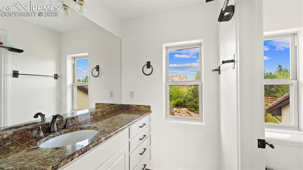 13625 Random Ridge View Colorado Springs, CO 80921 - Photo 38 of 50 a bathroom with a granite countertop sink a window and a mirror