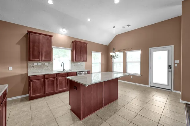 a large kitchen with kitchen island granite countertop a stove a sink dishwasher and a refrigerator