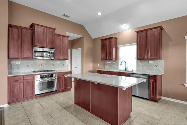 a kitchen with stainless steel appliances granite countertop wooden cabinets a sink and a stove