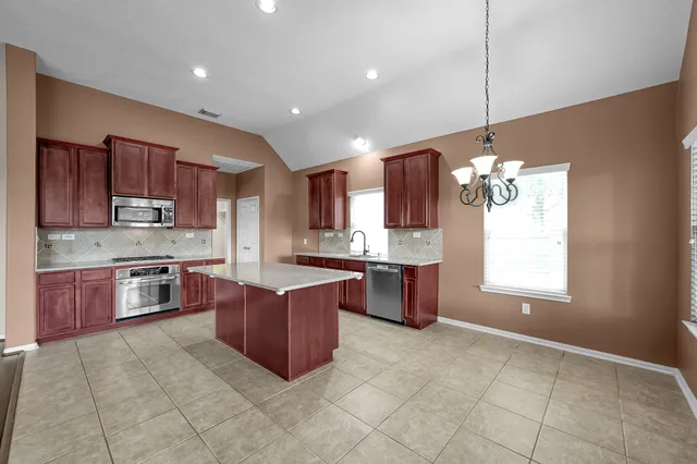 a large kitchen with stainless steel appliances granite countertop a stove sink and cabinets