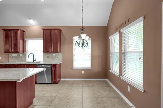 a kitchen with stainless steel appliances granite countertop a sink window and cabinets