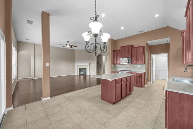 a large kitchen with granite countertop a large counter top cabinets and stainless steel appliances