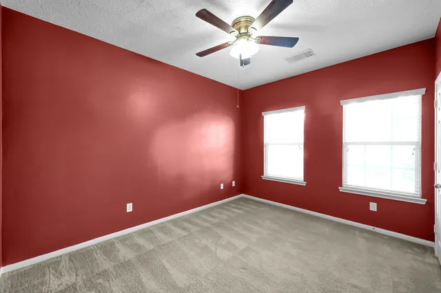 an empty room with windows and fan
