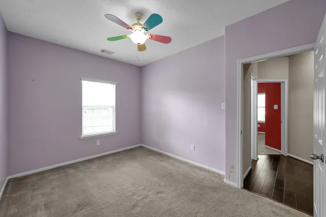 an empty room with a chandelier fan and windows