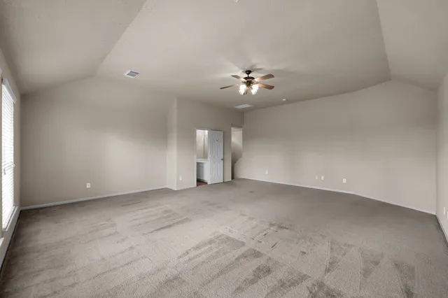 an empty room with chandelier fan and windows