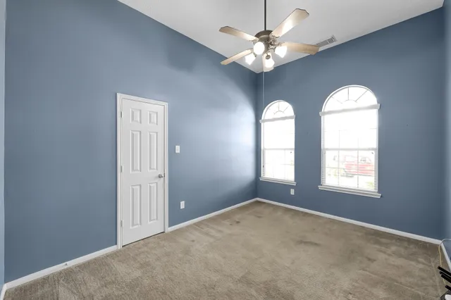 an empty room that has a window and ceiling fan