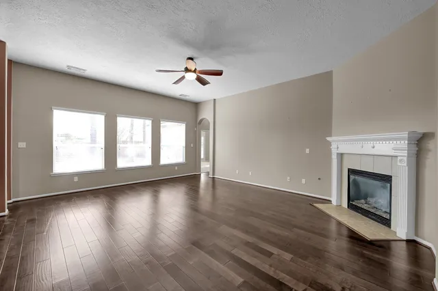 a view of an empty room with wooden floor fireplace and a window