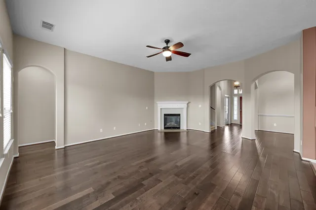 an empty room with wooden floor and ceiling fan