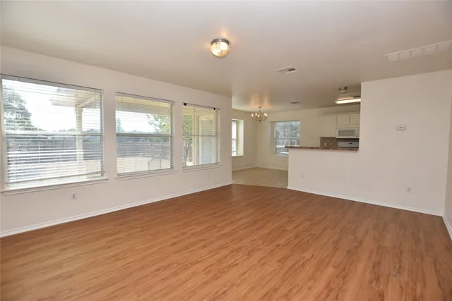 a view of an empty room with wooden floor and a window