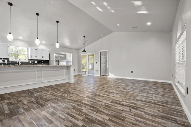 a view of a kitchen with stainless steel appliances kitchen island granite countertop a refrigerator a stove and a sink with wooden floor
