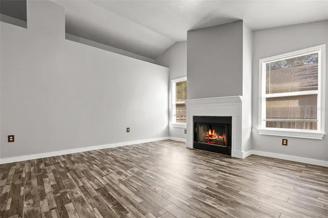 a view of wooden floor fire place and windows in a room