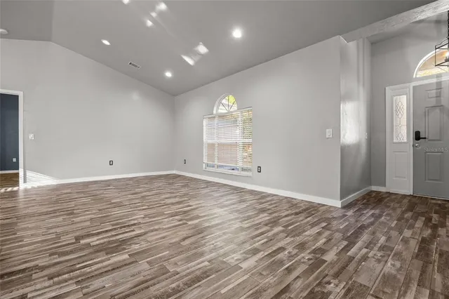 a view of empty room with wooden floor and fan