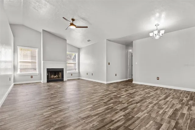 a view of a livingroom with a fireplace a ceiling fan and wooden floor