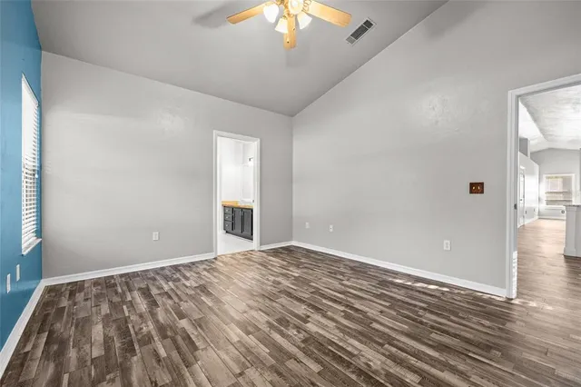 a view of an empty room with wooden floor and a chandelier fan