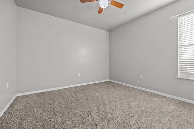an empty room with a window and a fan